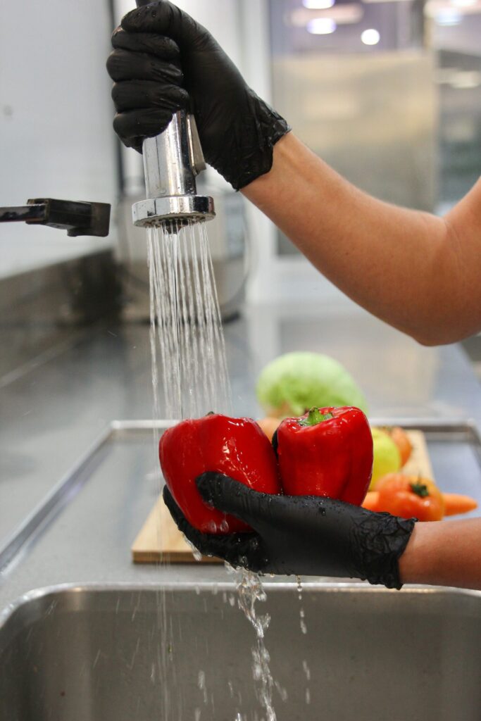 Lavado de pimientos rojos en cocina profesional de catering en Valencia