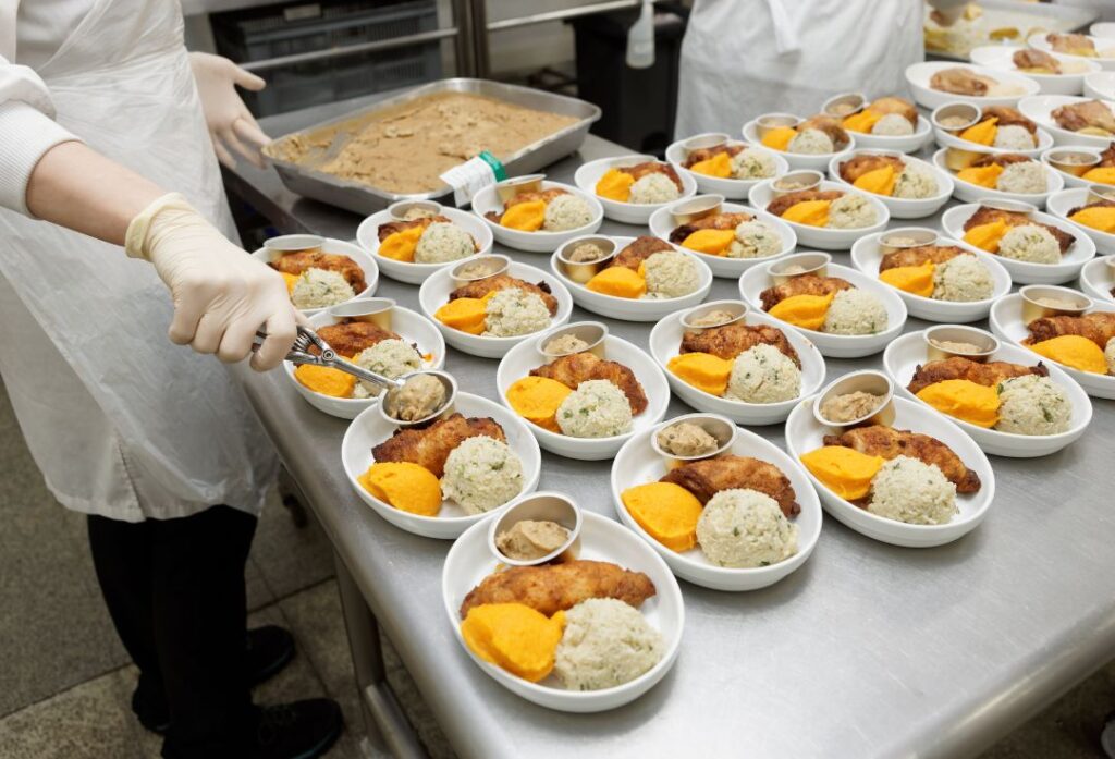 Cocineros preparando múltiples platos para catering en cocina profesional